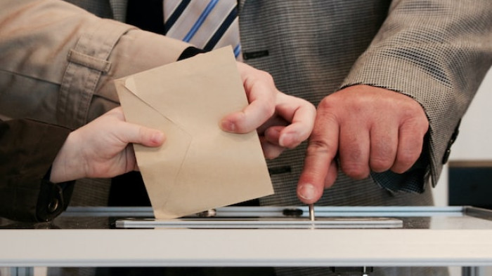 People depositing a vote in a ballot box
