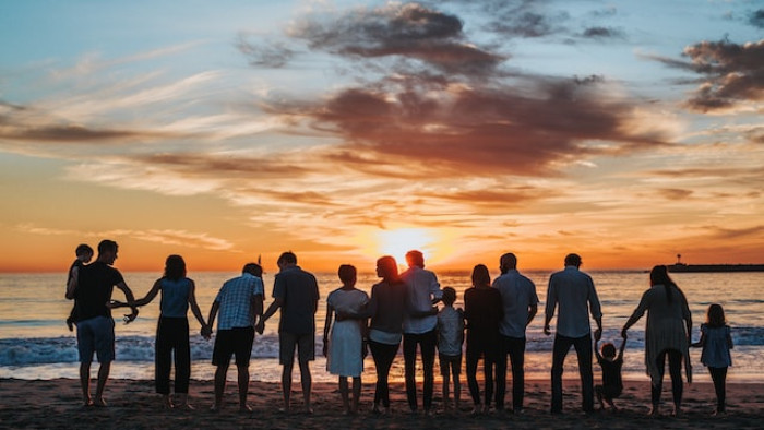 Grupo de gente de todas las edades en la playa observando una puesta de sol