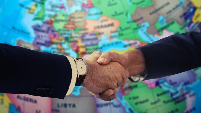 A handshake with a world map in the background