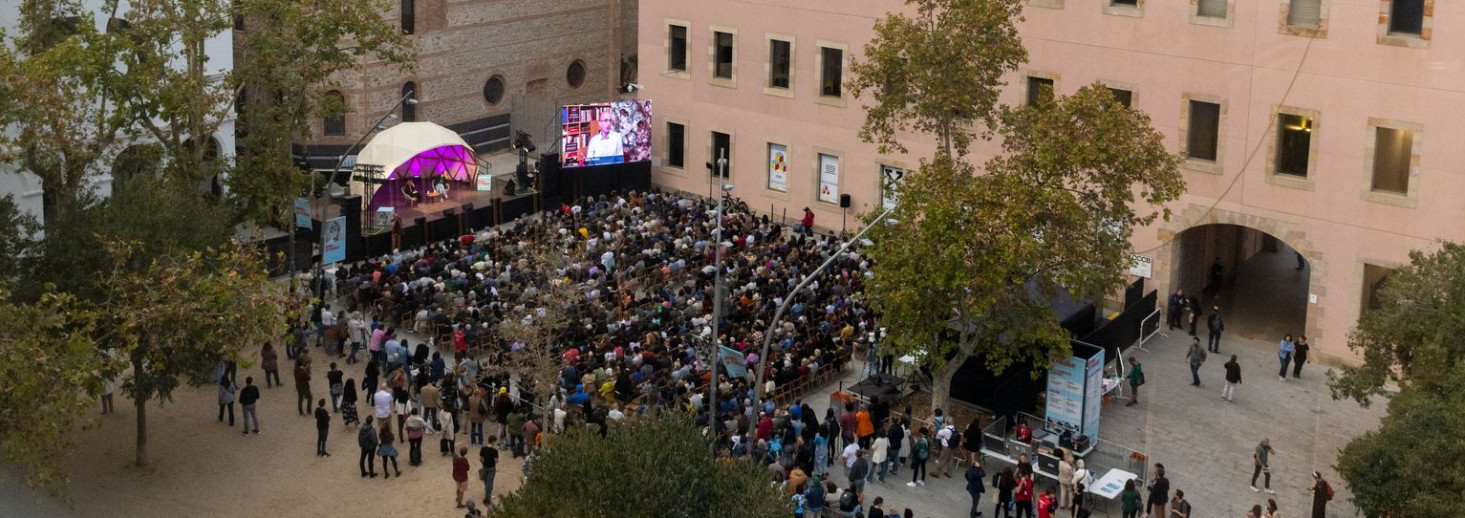 Una de les xerrades de la Biennal de Pensament de 2022 Plaça amb escenari i cadires amb gent escoltant una de les xerrades de la Biennal de Pensament de 2022